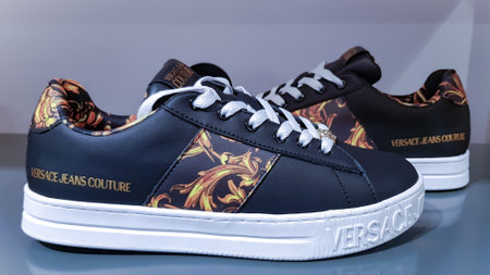 LATVIA, RIGA, JULY, 2022 - Versace Jeans Couture sneakers with golden design in Stockmann shopping mall. Riga, Latvia. Display of a pair of Italian designers sneakers with companyのeditorial素材