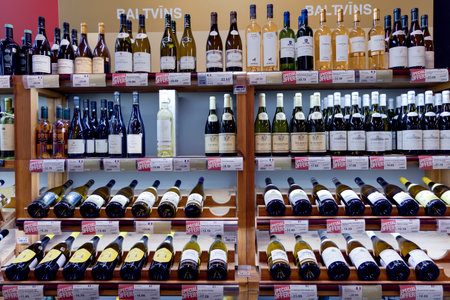LATVIA, RIGA, SEPTEMBER, 2022: Interior of modern wine boutique store. Wooden shelves with various of white wines with special prices in shopping mall, Riga, Latviaのeditorial素材