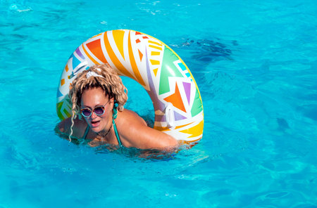 Pretty woman with curly blonde hair enjoying the relax of pool on an inflatable circle in Jurmala....