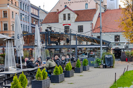 LATVIA, RIGA, SEPTEMBER, 2022: A group of friends drink beer on the open veranda of a cafe in the Riga Old Town, Latvia.のeditorial素材