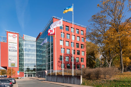 Latvia, Riga, October, 2022 - Modern multi storey building with glass walls as a business center for offices and shops surrounded by autumn park in Riga, Latviaのeditorial素材