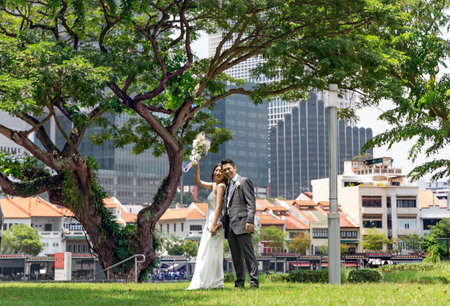 Southeast Asia, Singapore, November, 2022: Asian newly wed bride and groom celebrating marriage in beautiful park, Singapore.のeditorial素材