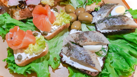 Open sandwiches with salted salmon, cream cheese and marinated herring with quail eggs on lettuce leaves. Morning healthy breakfast with fish. Quick and Healthy Sandwiches.の写真素材