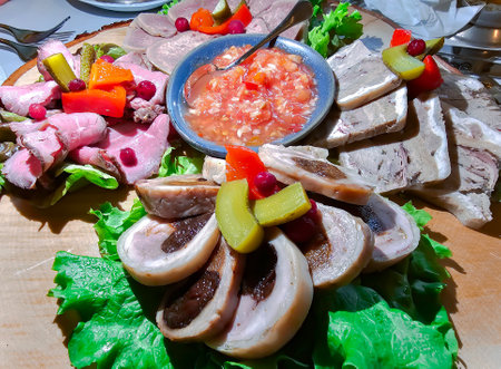 Large platter with various cuts of cold meat with pickled cucumbers and homemade adjika. Cold snacks for a holiday or a banquet.の写真素材