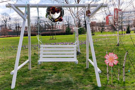 White Wooden Easter swing in a spring blooming garden. Spring outdoor activities for kids.の写真素材