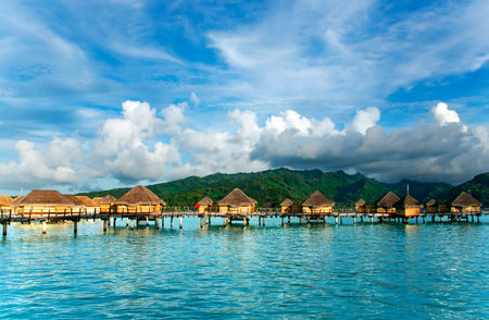 Overwater bungalows stretching and a wooden bridge out across the lagoon in Bora Bora island, Tahiti. Romantic honeymoon destination.の写真素材