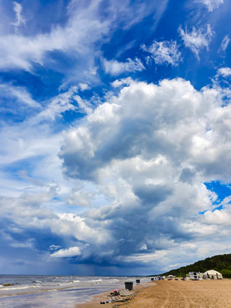 Lush cumulus clouds over Baltic sea in Jurmala, Latvia. nature environment concept. Cumulus clouds turn into thunderstorms. Waves flooded the shore and the clouds are reflected inの写真素材