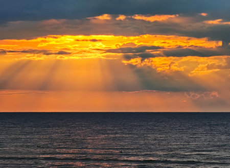 Magic sunset with dark storm clouds and penetrating sunbeams above the Baltic sea in Jurmala, Latviaの写真素材