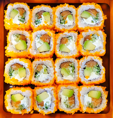 Sushi roll with smoked salmon, avocado and soft cheese on a wooden plate close-up.Traditional delicious fresh sushi roll set. Sushi menu. Japanese food restaurant. Asian food.の写真素材