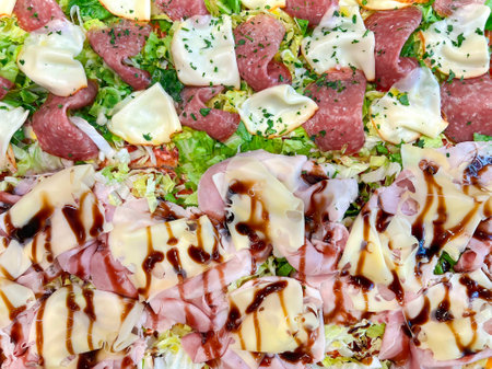 Fresh Italian pizza with ham, salami and cheese with green salad closeup. Tasty delicious Italian homemade pizza.の写真素材