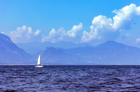 A lone sailboat on Lake Como with the Italian Alps in the background in the Lombardy region in northern Italy.の写真素材