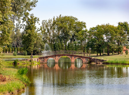 Beautiful park with a lake and an old red brick stone bridge in Sodeliskiu dvaras, Birzai, Lithuaniaの写真素材
