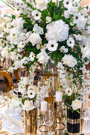 Large luxurious wedding bouquet of white flowers on a festive table with beautiful dishes and candles in a restaurant close-upの写真素材
