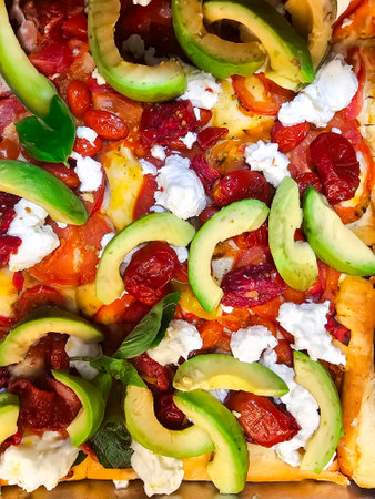 Spanish delicious pizza with avocado, sun-dried tomatoes and soft cheese close-up. Freshly prepared healthy food.の写真素材