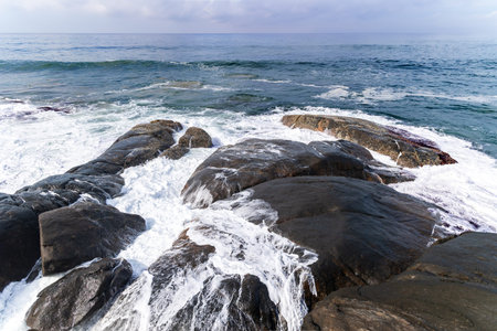 Huge volcanic boulders are washed by the foaming waves of the Indian Ocean coast at Sri Lanka, Asia.