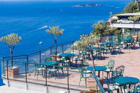 Open veranda of cafe with blue tables overlooking Mediterranean sea on Capri island, Italyの写真素材