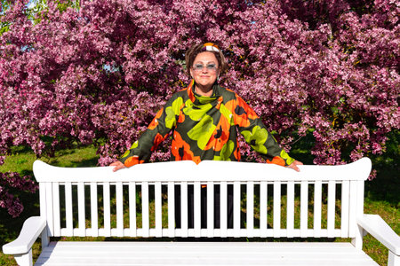 Pretty woman in a bright jacket enjoying the view and smell of blooming cherries in the garden. Concept of beauty of the surrounding nature.の写真素材