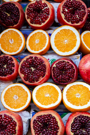 Rows of sliced ââripe pomegranates and juicy oranges displayed at a farmers market in Israelの写真素材