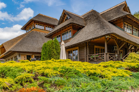 Modern old style thatched log cottage with beautiful landscaping located right on the shore of Lake Lilaste. Latvia.の写真素材