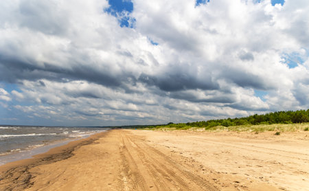 Panorama of a sandy and deserted beach of the Baltic Sea with fluffy clouds in the sky in Jurmala, Latviaの写真素材