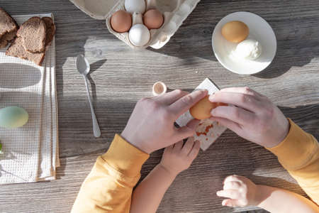 A dad celebrates Easter with his young son. They beat eggs, eat eggs and have breakfast. Dad teaches the childの写真素材