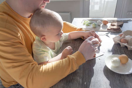 A dad celebrates Easter with his young son. They beat eggs, eat eggs and have breakfast. Dad teaches the childの写真素材