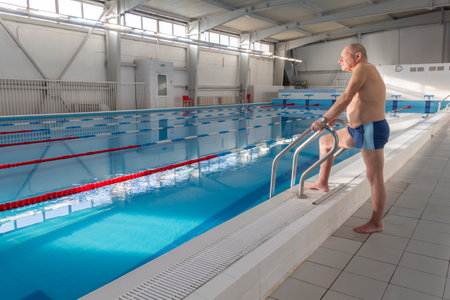 An elderly man is actively engaged in swimming and sports in the pool in a retired sports complexの写真素材