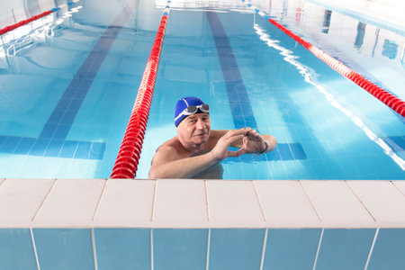 An elderly man is actively engaged in swimming and sports in the pool in a retired sports complexの写真素材