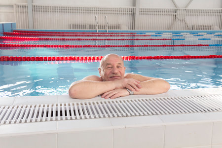 An elderly man is actively engaged in swimming and sports in the pool in a retired sports complexの写真素材