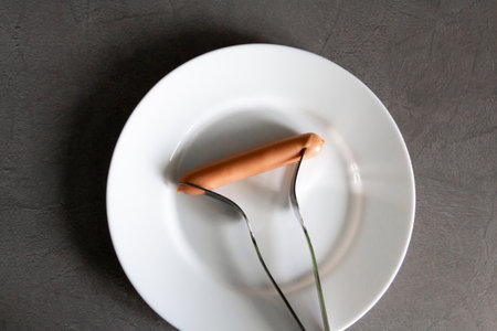 Two people in a family are forced to share a sausage for two with a fork due to lack of money and livelihood due to sanctions and hunger caused by the war.の写真素材
