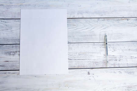 A white sheet of a4 paper and a ballpoint pen for office work and university studies on a light, wooden background.の写真素材