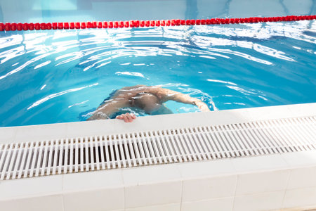 A pensioner of 70 years rests and swims in the pool in a clean, blue pool in the fresh air on...