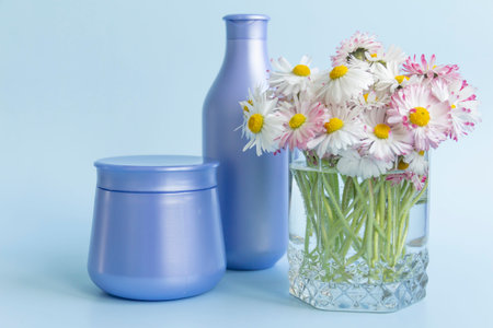 A bouquet of fresh flowers, daisies on green stems are in a glass with clean water and two purple...