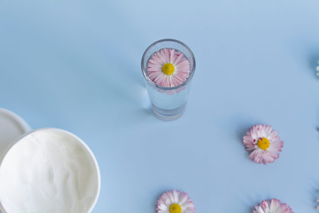 Fresh flowers, daisies are laid out in a corner, with a glass of clean water and a white jar with a...