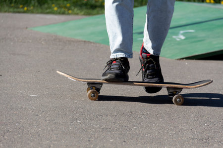 Athletic legs of a teenager ride a skateboard on a sports field, on the street. Active extreme...