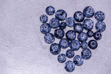 The heart is made of fresh, healthy blueberries on a gray table. Farm vitamins in summer.の写真素材