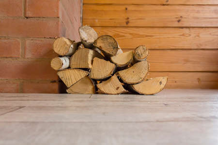 Birch firewood lies on the floor of a wooden house near the fireplace to heat the house on cold days..の写真素材