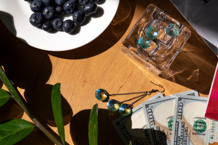 Blueberries in a white plate on a wooden table against the background of American dollars, magazines...