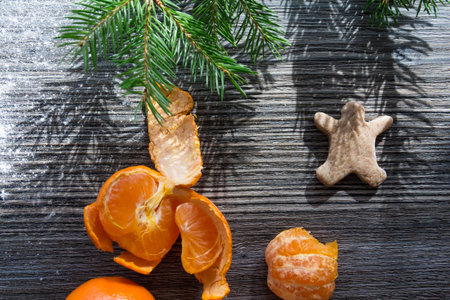 Tangerines, gingerbread and cookies on a wooden table, sprinkled with white flour in the form of...