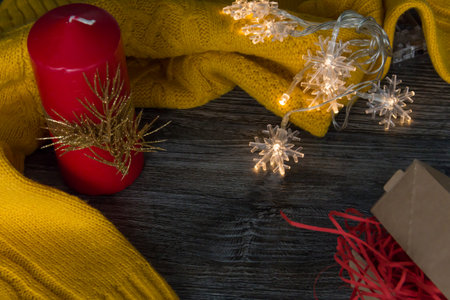 Christmas decorations and decorations with a yellow sweater and a red candle on a wooden surface.