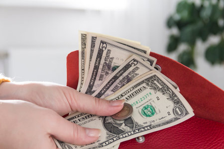 Women's hands in a yellow sweater are holding an open, red purse with money..の写真素材