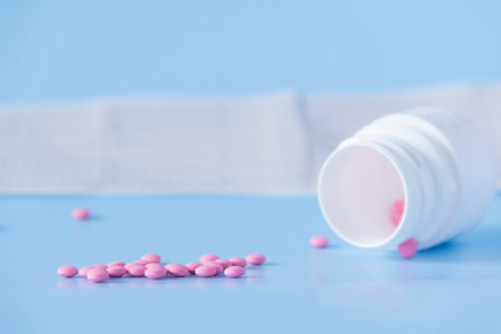 A large handful of pink pills poured out of a white jar on an electrocardiogram of the heart, on a blue background. The concept of a healthy lifestyle and timely medical examinationの写真素材
