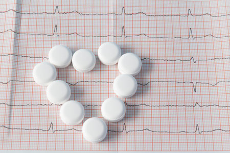 A heart made of large, white drugs on an electrocardiogram of the heart, on a blue background. The concept of a healthy lifestyle and timely medical examinationの写真素材