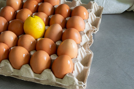 Chicken eggs lie in a tray on a kitchen surface with a yellow lemon. Buying products and goods in the storeの写真素材