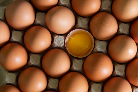 Chicken eggs lie in a tray on the kitchen surface with a broken yellow yolk. Buying products and goods in the storeの写真素材