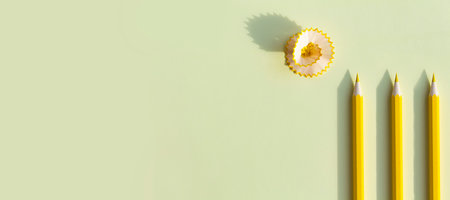 The yellow, colored pencil for drawing in the album is sharpened and lies on a yellow background with a pronounced shadow on a sunny day from bright, sunlight.の写真素材