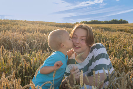 A little boy and his teenage brother are having fun walking in a field with ripe wheat. Grain for making bread. the concept of economic crisis and hungerの写真素材