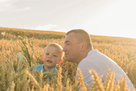 Dad and his little son are having fun walking in a field with ripe wheat. Grain for making bread. the concept of economic crisis and hungerの写真素材