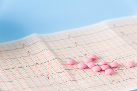 A large handful of pink pills lie on the electrocardiogram of the heart on a blue background. The concept of a healthy lifestyle and timely medical examinationの写真素材