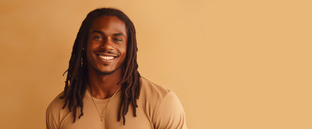 Portrait of an elegant sexy smiling African man with dark and perfect skin and long hair, on a creamy beige background.の素材